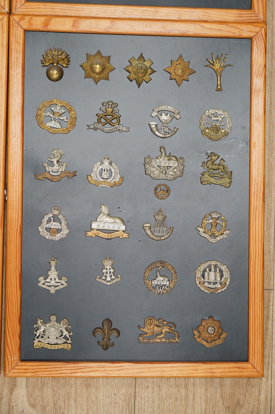 A collection of ninety-seven military cap badges mounted on four boards including; The City of London Yeomanry, Duke of Lancaster‘s Own, Bedfordshire Regiment, Leicestershire Regiment, Seventh Battalion Hampshire Regimen